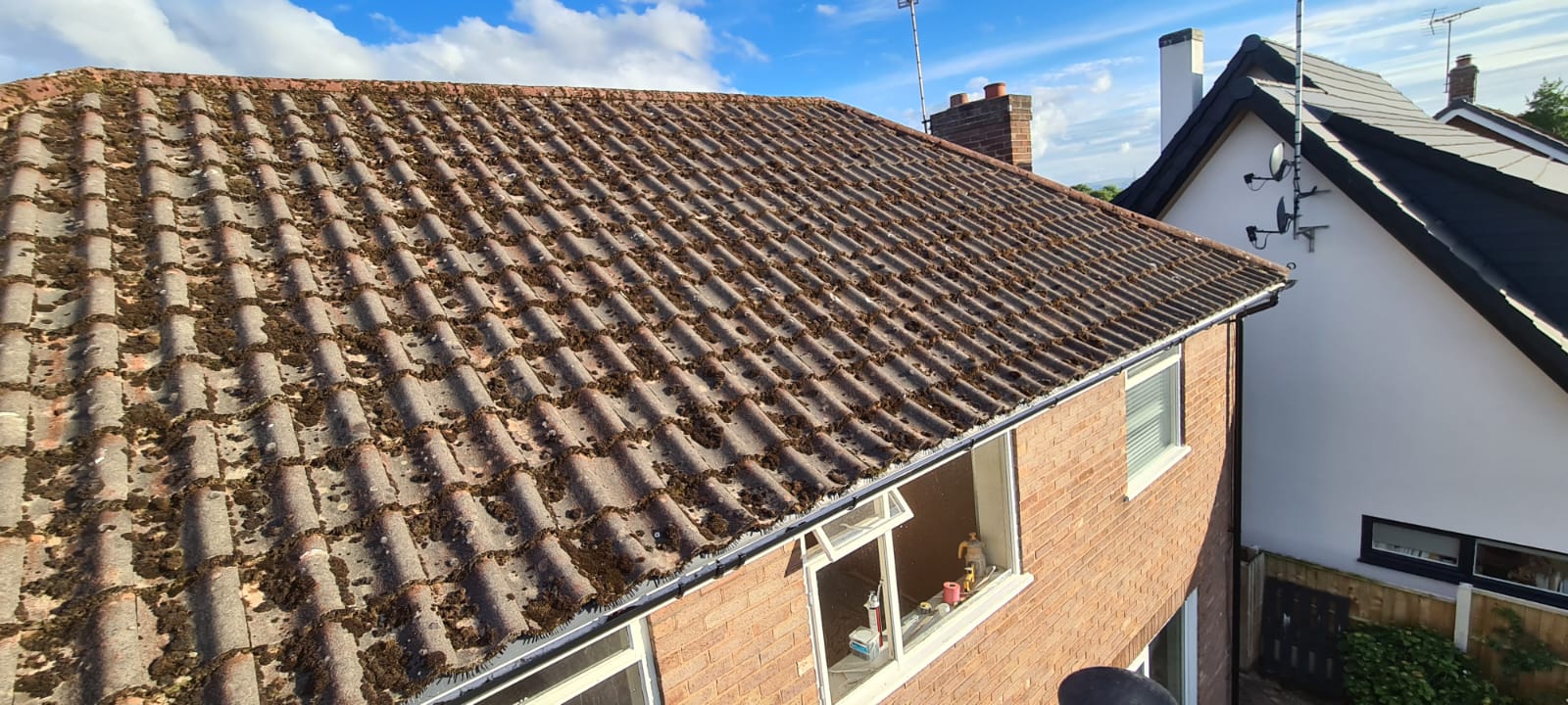 Roof cleaning pole clearing moss from a Wirral tiled roof