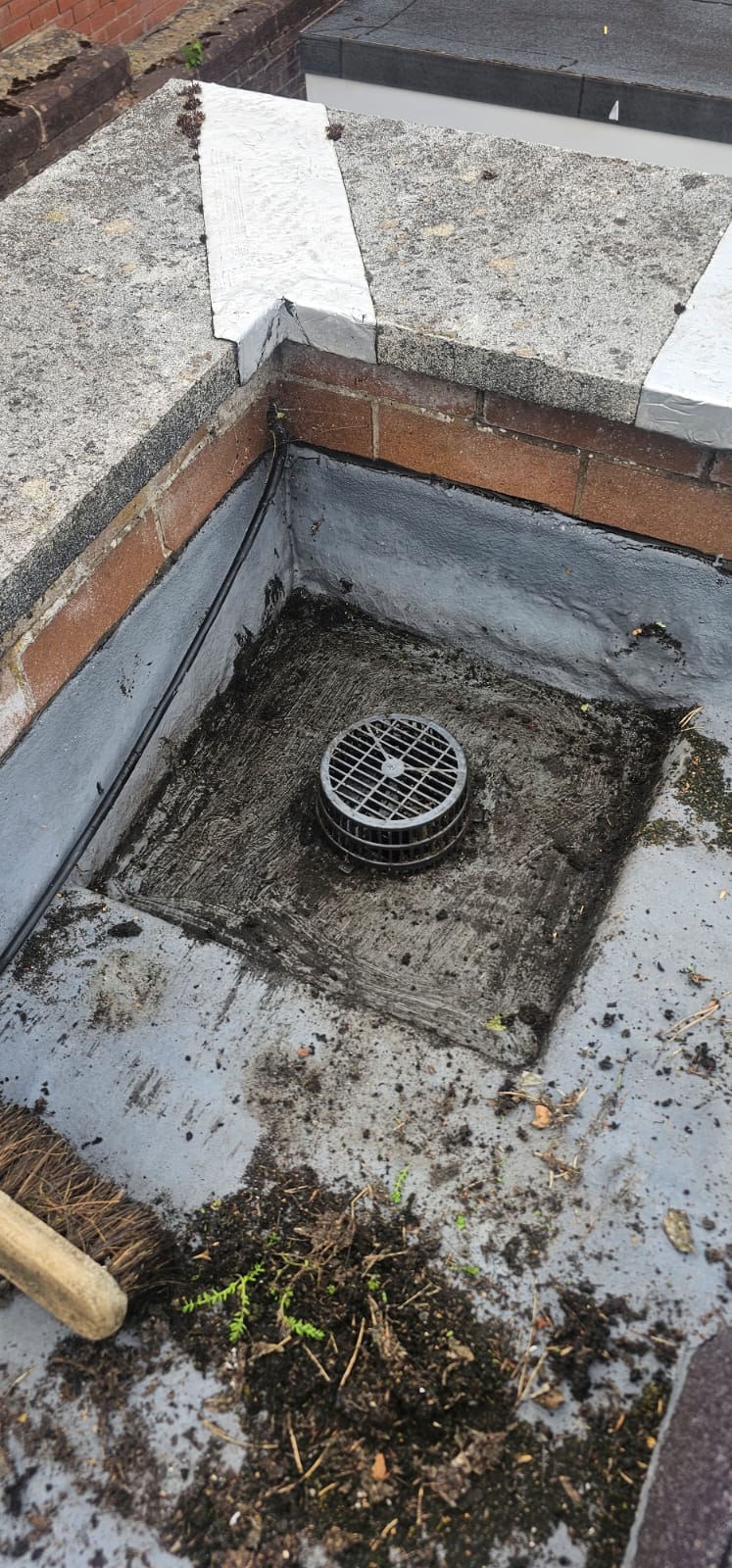Standing water and debris in a gutter beside corrugated roofing in the Wirral