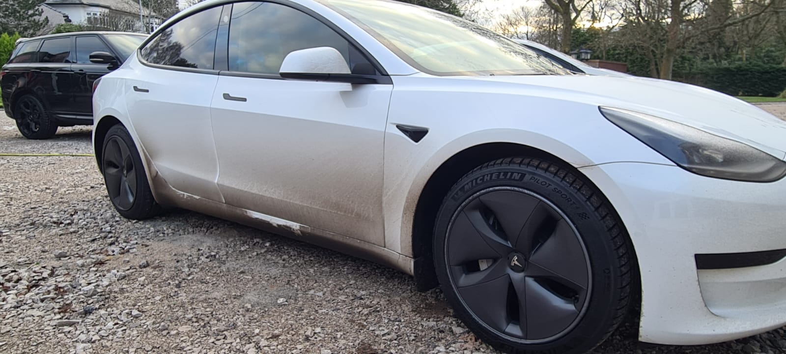 Dirty white electric car before a mobile valet in the Wirral